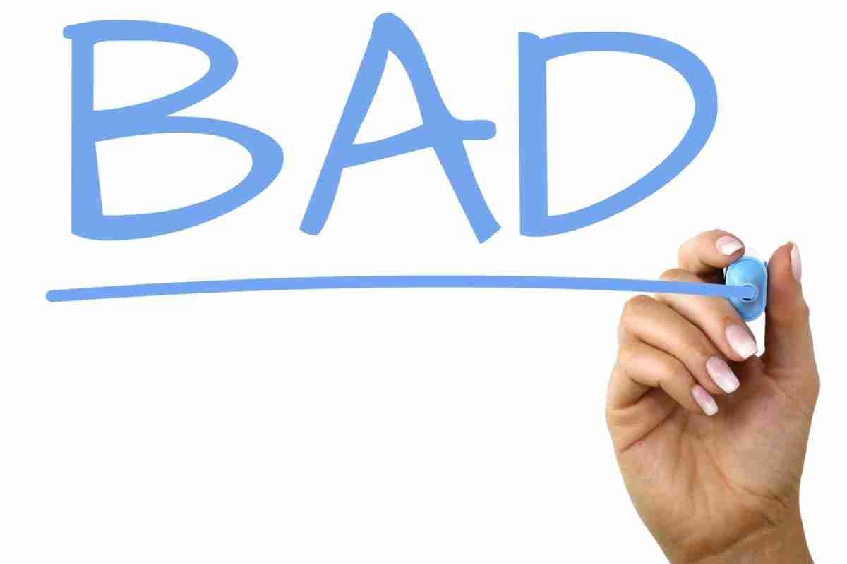 A hand holding a marker pen appears to be writing the word "BAD" in blue, with an underline, on a white background.